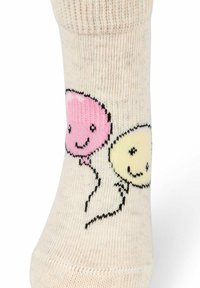 Calzino color crema con disegni di palloncini rosa e gialli con faccine sorridenti. Il materiale sembra morbido, con una trama a maglia e un motivo sottile su tutta la superficie.