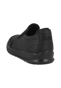Zapato negro tipo slip-on con material superior liso, forma redondeada, suela texturizada y costuras acentuadas en el talón y los lados.