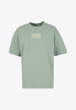 Mehitatud roheline puuvillane t-särk lühikeste varrukatega, ümar kaelus ja julge "KANI STUDIOS" logo beežil värvil rinnal. Klassikaline mugav istuvus.