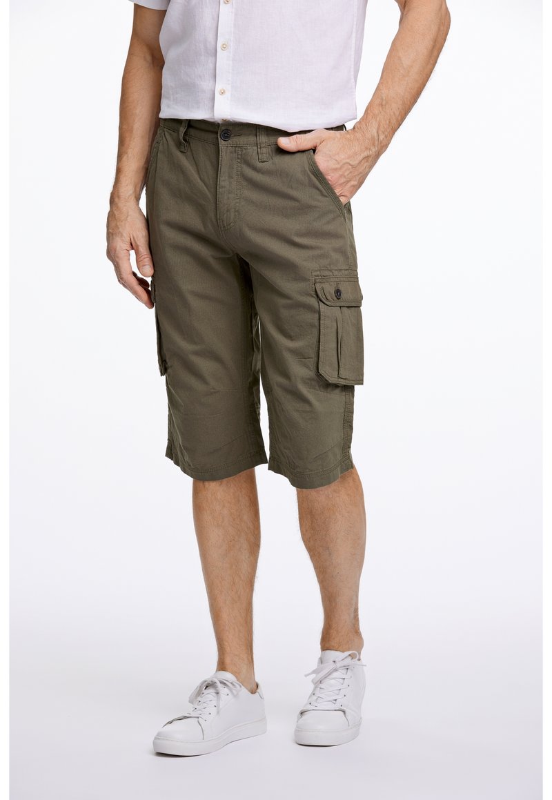 Olivgrüne Cargo-Shorts aus Baumwolle, mit zwei großen seitlichen Taschen, genähten Säumen und lockerer Passform, kombiniert mit weißen Sneakers.