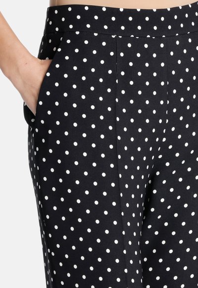 Pantalons noirs avec des pois blancs, avec une texture lisse, un design droit et des poches latérales. Coupe ajustée avec une taille discrète.
