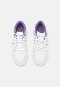 White leather sneakers with purple accents, featuring a rounded toe, lace closure, and textured outsole. Brand name visible on the tongue.