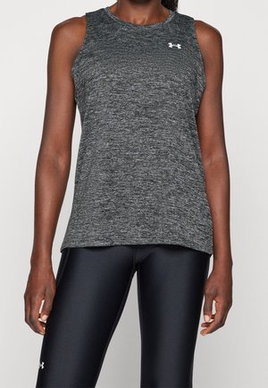 Atletisk person iført en ærmeløs grå tekstureret top og sorte skinnende leggings med synlige Under Armour-logoer.