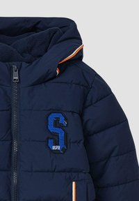 Marineblaue Steppjacke mit gestepptem Muster, ausgestattet mit einem gestickten "S"-Logo in Blau. Orangefarbene Akzente entlang des Reißverschlusses und der Kapuze.