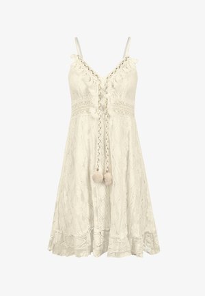 Robe blanche en dentelle avec des fines bretelles, motifs floraux, un lien tressé à l'avant avec des pompons et une finition évasée.