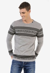 Grauer Pullover mit langen Ärmeln und horizontalen schwarzen Streifen, ausgestattet mit einem Rundhalsausschnitt sowie gerippten Bündchen und Saum. Getragen mit blauen Jeans.