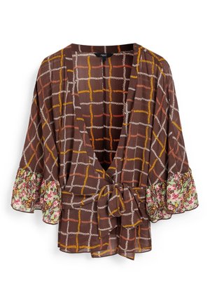 Blouse marron avec motif quadrillé cousu en orange, rouge et blanc, manches à volants fleuries et nœud noué à l’avant.