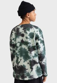 Long-sleeve tie-dye shirt in light green, featuring dark green and black patterns. Soft fabric with a relaxed fit and round neckline.