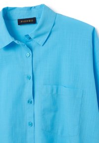 Camisa de manga corta azul claro con cuello estructurado, bolsillo frontal y cierre de botones con botones a juego; tela texturizada.