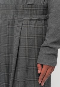 Grijze geruite broek van een gestructureerde stof, met een elastische tailleband en zijplooien. Het ontwerp bevat fijne lijnen in lichtere tinten.