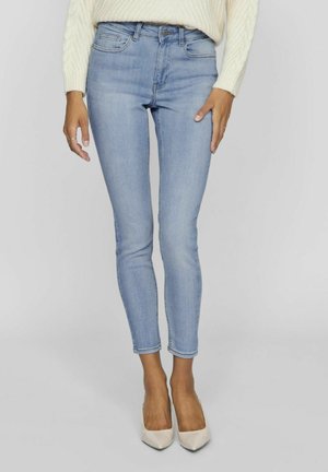 Jeans skinny bleu clair en denim, avec une taille mi-haute, un design à cinq poches et un léger dégradé sur les jambes.