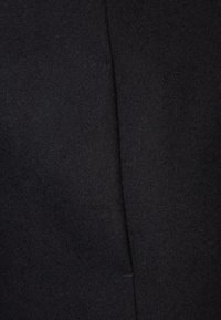 Svart ulltyg med en slät textur, med en central söm och utan synliga mönster eller beslag. Lämplig för skräddarsydda plagg.