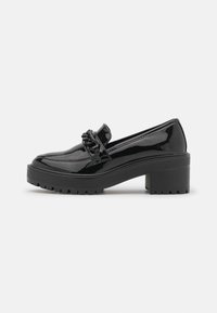 Mocassin en cuir verni noir avec un large talon carré et un détail de chaîne décoratif sur le dessus, photographié sur fond blanc.