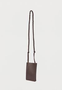Small dark brown leather crossbody bag with a long braided strap and minimal stitching details on the front.