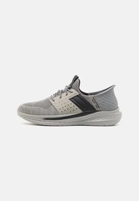 Chaussure de sport légère en mesh gris avec des accents gris foncé, des perforations respirantes et une semelle coussinée présentant un design texturé.