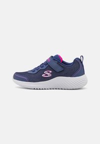 Chaussure de sport marine avec un dessus texturé, des accents roses, une sangle ajustable et une semelle en caoutchouc blanc avec un motif de semelle en zigzag.