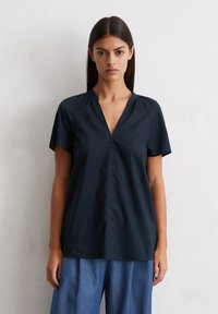 Navy blue short-sleeve shirt with a V-neck and gathered shoulder seams. Made of smooth, lightweight fabric. Straight hemline.