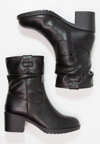 Czarne skórzane botki za kostkę o luźnym fasonie, z bocznym zamkiem błyskawicznym i masywnym obcasem. Podeszwa posiada wzór zapewniający dobre grip.
