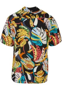 Chemise multicolore arborant un imprimé tropical audacieux de feuilles et d'animaux sur fond noir. Manches courtes, coupe décontractée et col camp.