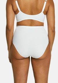 Une culotte blanche taille haute en tissu lisse avec un design sans couture et un empiècement picot le long des bords, vue de dos.