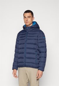 Mornarska puffer jakna s patentnim zatvaračem sprijeda i podesivim kapuljačom. Sadrži akcentne detalje u tirkiznoj boji i horizontalni kviltani dizajn za bolju izolaciju.