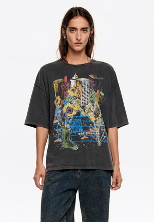 Camiseta gris de gran tamaño con un diseño gráfico colorido de flores y edificios, hecha de una tela suave y con un corte relajado.