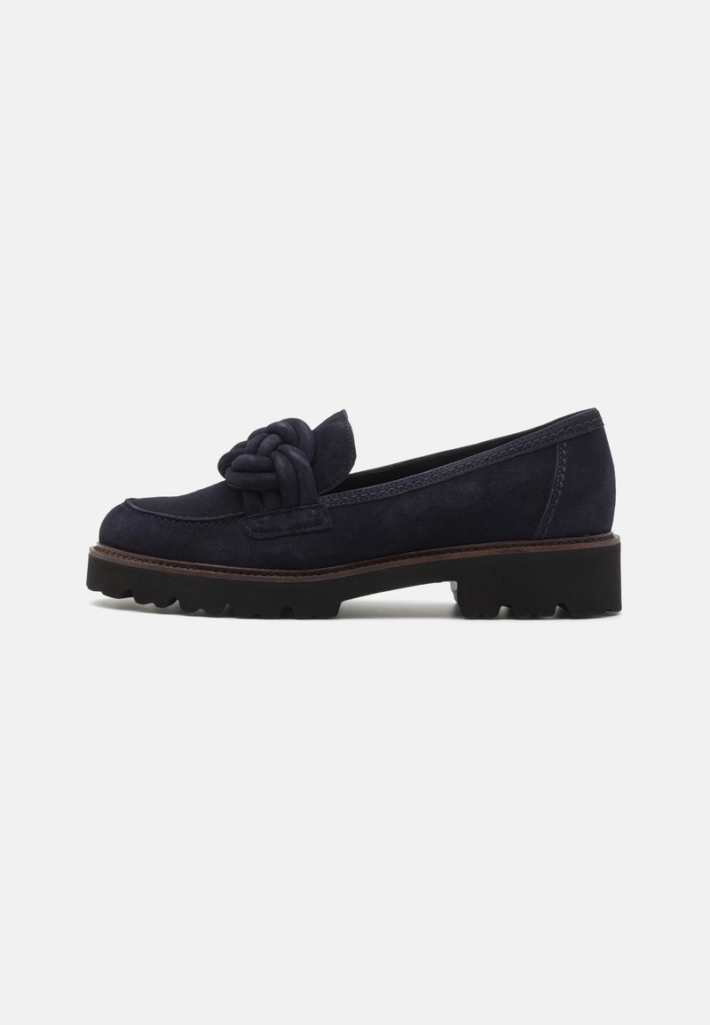 Mocassin en daim bleu foncé avec semelle noire épaisse et nœud tressé décoratif sur le dessus, vue de côté sur fond blanc.