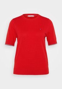 Czerwona krótka bluzka dzianinowa z ribbowym dołem i mankietami, małym logo na lewej piersi oraz paskowym wykończeniem krawędzi rękawów.