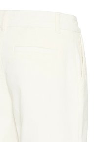 Pantalones de pana blanca con textura acanalada, diseño de cinco bolsillos, trabas para cinturón y un único bolsillo trasero.