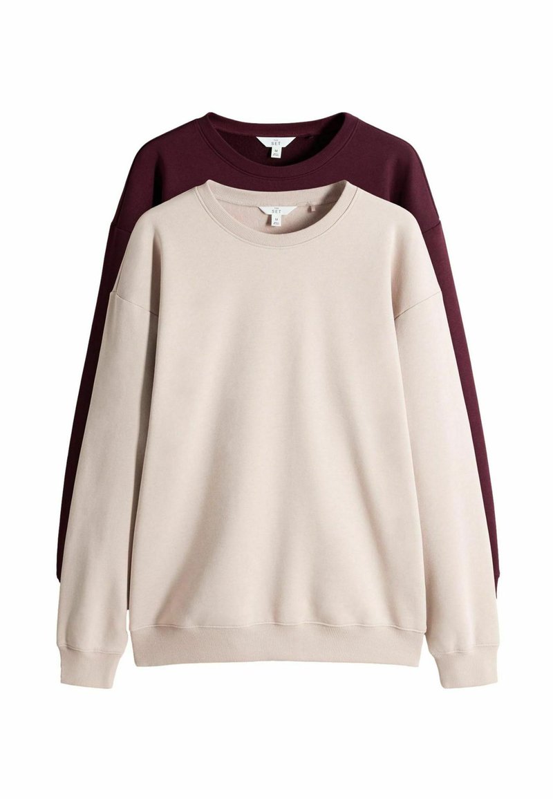 Due felpe esposte, una beige e una bordeaux. Entrambe hanno un collo rotondo, maniche lunghe e sono realizzate in un tessuto morbido.