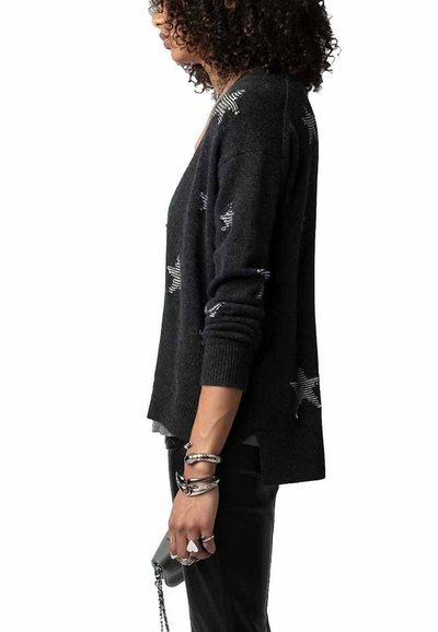 Cardigan noir avec des motifs d'étoiles argentées, des poignets côtelés et des fentes latérales. Texture douce, coupe décontractée et design légèrement plus long à l'arrière.