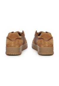 Bruine suède sneakers met een glad leren paneel, ronde neus en rubberen zolen. Bevat minimale merkidentificatie op de hiel en textuuraccenten.