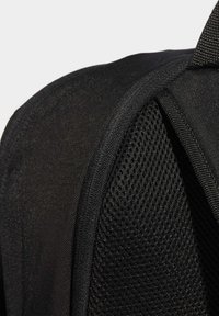 Sac à dos en tissu noir avec un panneau en maille texturée, des bords lisses et des coutures renforcées. Présente un design épuré pour fonctionner de manière optimale.