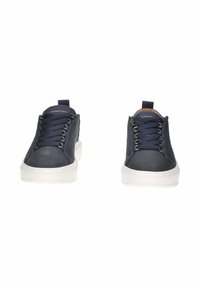Un paio di sneakers in pelle blu navy con suole bianche e lacci blu scuro, viste frontalmente su uno sfondo bianco.