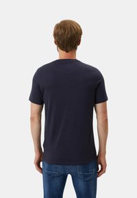 T-shirt in cotone blu navy con maniche corte, caratterizzato da un colletto rotondo e una texture liscia. Indossato con jeans blu, mostra un taglio casual.