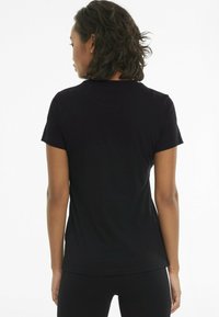 Czarna koszulka z krótkim rękawem, o okrągłym dekolcie i dopasowanym kroju. Wykonana z miękkiej bawełny, o gładkiej strukturze i subtelnych detalach szwów.