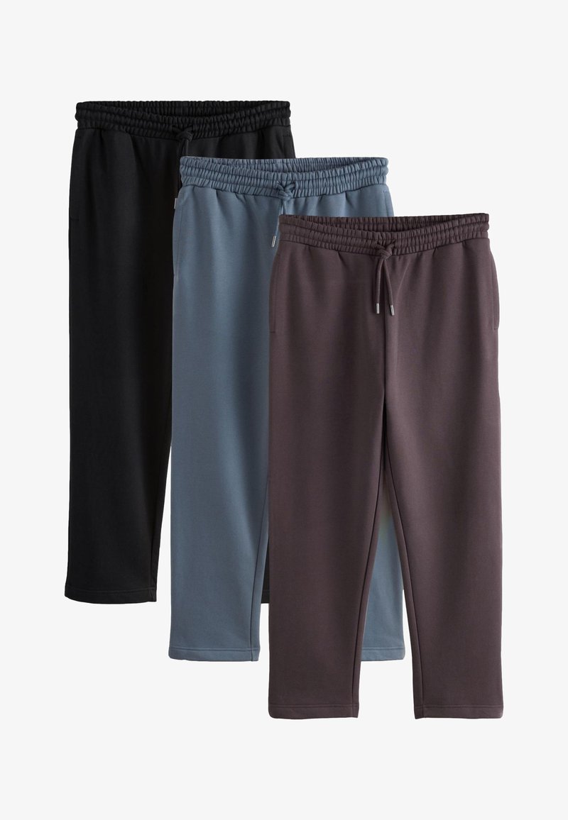 Tre paia di pantaloni della tuta con vita elasticizzata e coulisse, nei colori nero, blu e marrone scuro, disposti sovrapposti su uno sfondo bianco.