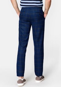 Niebieskie spodnie w kratę wykonane z tkaniny, charakteryzujące się slim fit, dwiema tylnymi kieszeniami z guzikami, wykończone jasnobrązowymi akcentami.