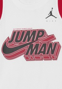 Biała siateczkowa koszulka bez rękawów z czerwoną i czarną grafiką "JUMP MAN", czarnym logo Nike oraz przewiewną teksturą.