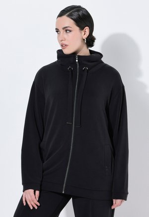 Le sweat à capuche zippé noir présente un col haut, des cordons de serrage ajustables et des poches latérales. Fabriqué en tissu doux et texturé avec une coupe décontractée.