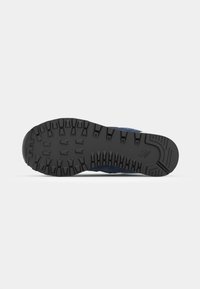 Black rubber shoe sole with deep treads and grooves; features a slight curvature, textured surface, and a layered blue upper section.