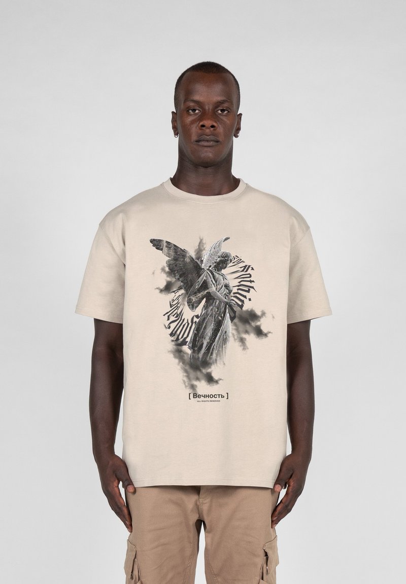 Beige bomulds t-shirt med en sort-hvid engel grafik og teksten "[Вечность]" nedenfor, korte ærmer og en afslappet pasform.