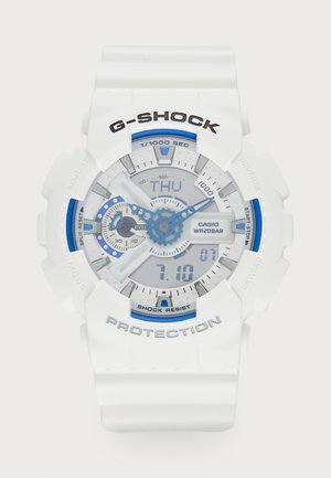 Valge G-SHOCK kell siniste detailidega. Digitaalne ja analoogne kuva, tekstuuriga rihm, veekindel kuni 20 baari, märgistatud nupud ja selge displei.
