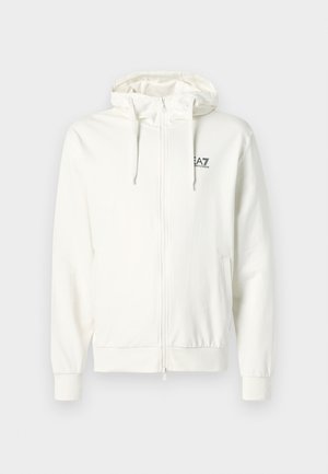 Balts zip-up džemperis, kas izgatavots no mīkstas auduma. Iezīmēts ar kapuci ar auklu, elastīgām piedurknēm un mazu logotipu iespiestu uz krūtīm.