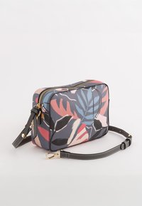 Rektangulær crossbody taske i syntetisk materiale, med et flerfarvet bladmønster på en marineblå baggrund, guld lynlås og sort rem.