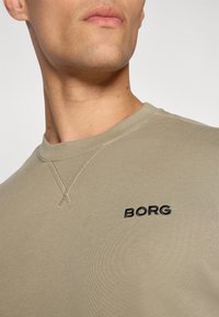 Khaki sweatshirt with round neckline, featuring black embroidered "BORG" logo and subtle textured stitching details on the shoulder.