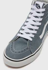Grijze hoge suède sneakers met witte veters en stiksels, voorzien van een witte zijstreep en een getextureerde rubberen zool.