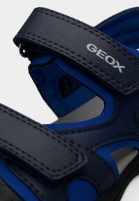 Μπλε και ναυτικό σανδάλι με ρυθμιζόμενους ιμάντες Velcro, υφασμάτινο συνθετικό επάνω μέρος με υφή και ανοίγματα για αναπνοή.