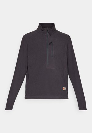 Mørkegrå fleecepuls med høy krage, kvart glidelås og en frontlomme. Har et lite logo-patch nederst til høyre. Glatt tekstur.