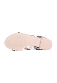 Flate sandaler med en beige gummisåle. Overdelen har en blanding av hvite, svarte og grå slangeskinnmønstrede stropper. Teksturert fotseng for godt grep.